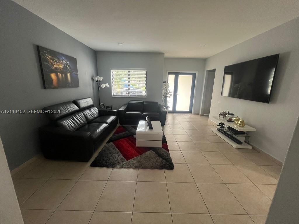 Neutral-toned interior featuring large-format ceramic tile flooring, recessed ceiling lighting, and a dual-pane entry door