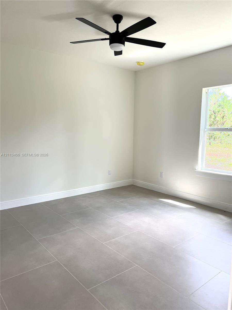 Neutral-toned interior featuring large-format tile flooring, matte black ceiling fan with integrated lighting, and energy-efficient window Neutral-toned interior featuring large-format tile flooring, matte black ceiling fan with integrated lighting, and energy-efficient window