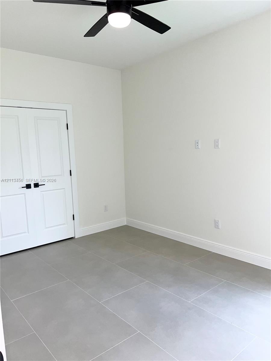 Neutral-toned tile flooring, double-panel doors with matte black hardware, and a ceiling-mounted light fixture with a fan Neutral-toned tile flooring, double-panel doors with matte black hardware, and a ceiling-mounted light fixture with a fan