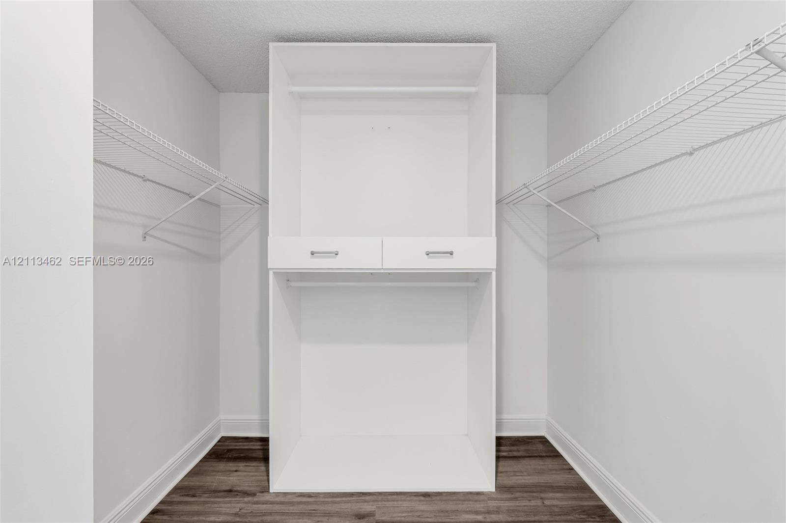 Storage closet featuring white built-in shelving, dual drawers with metal hardware, and dual-level wire racking, complemented by wood-finish flooring