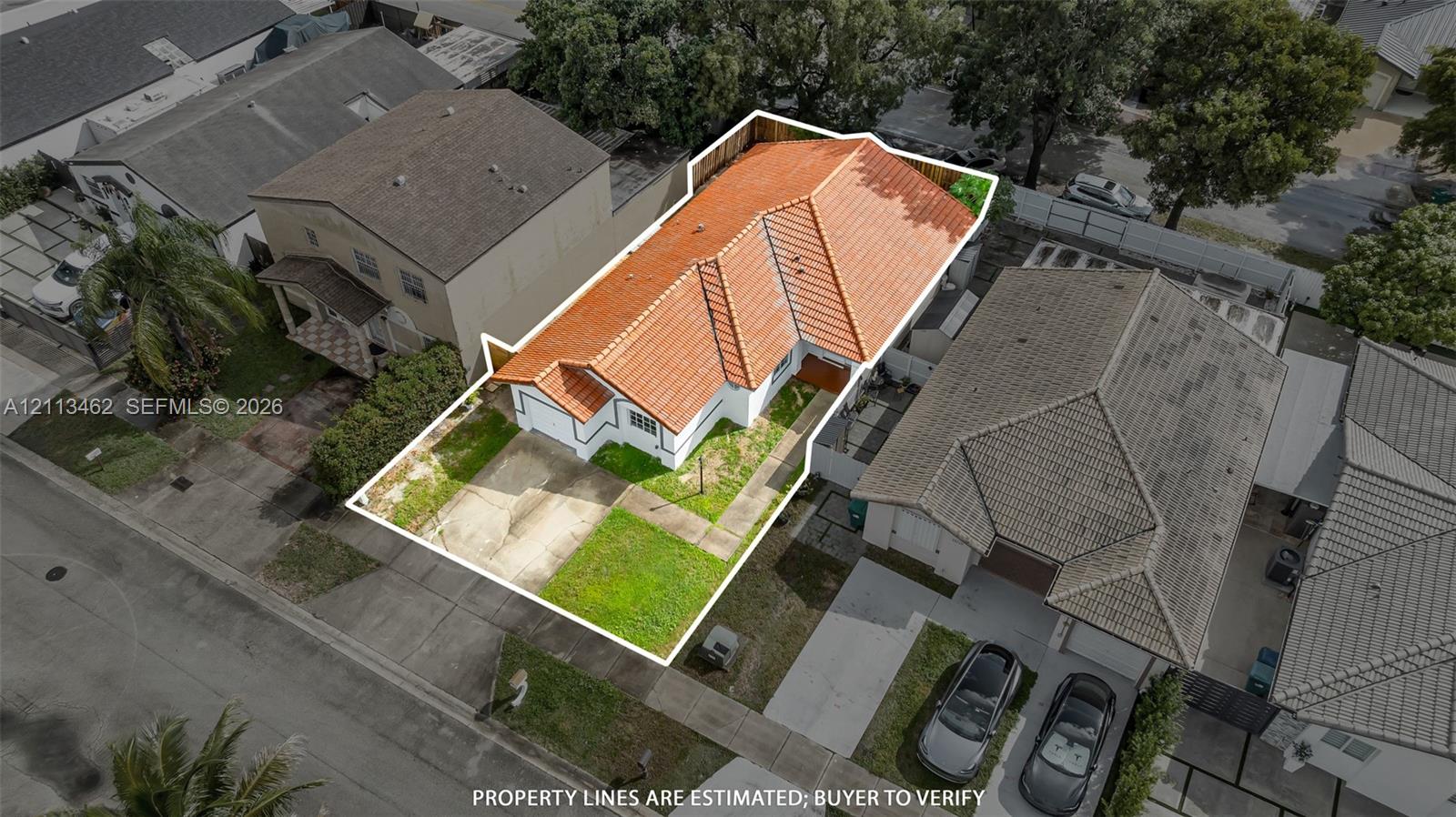 Single-story residence featuring a terracotta-tiled roof, white stucco exterior, attached garage, and a fenced backyard
