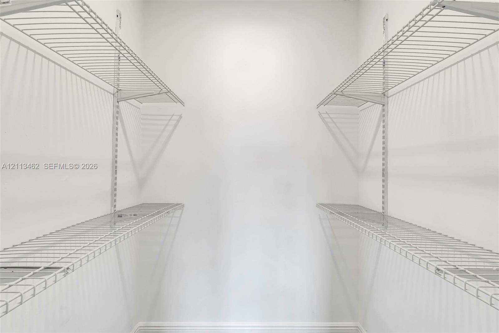 Storage space featuring dual-level white wire shelving units mounted on vertical wall tracks