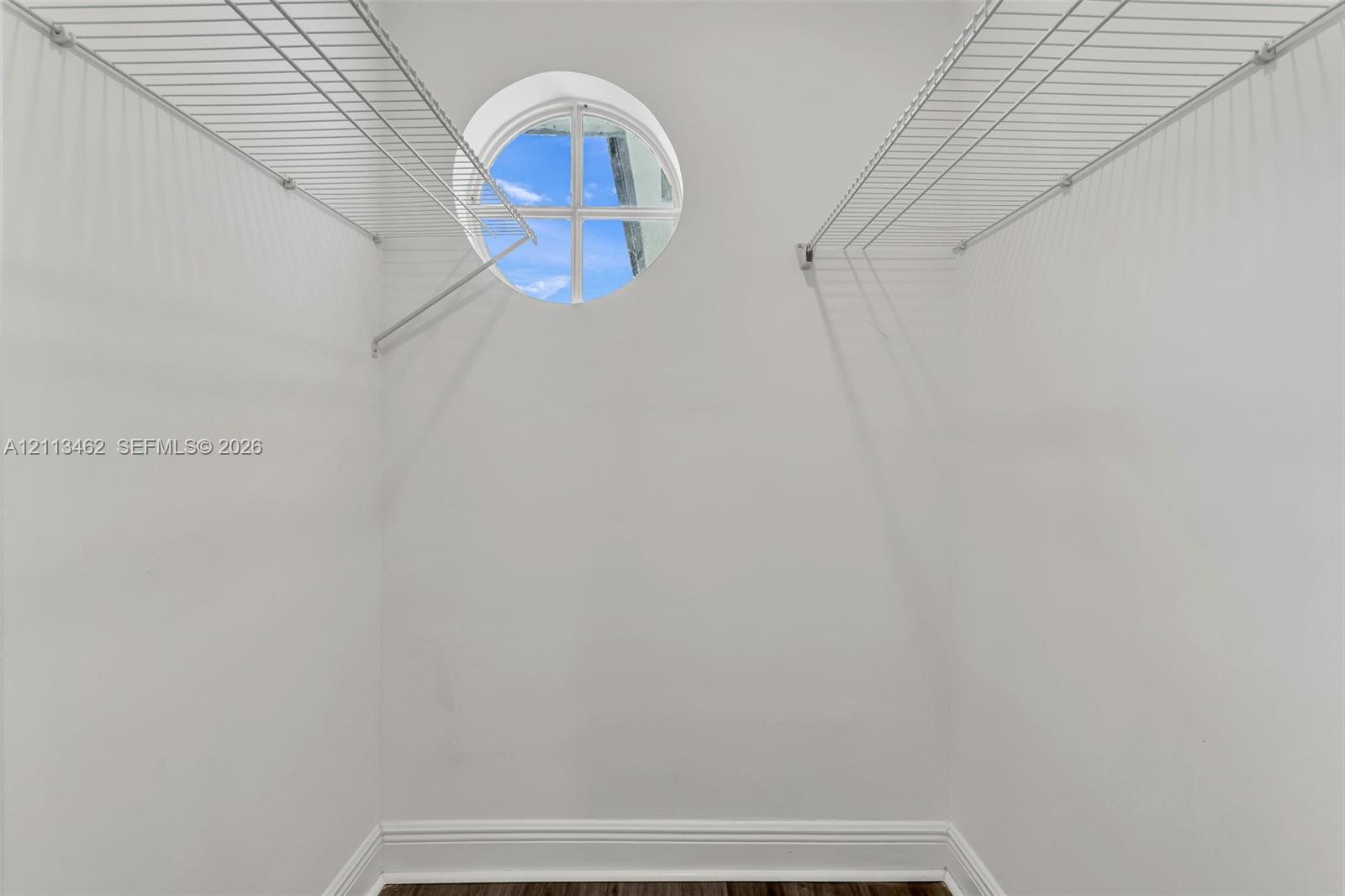 Storage space featuring white wire shelving and a circular window with divided light detail