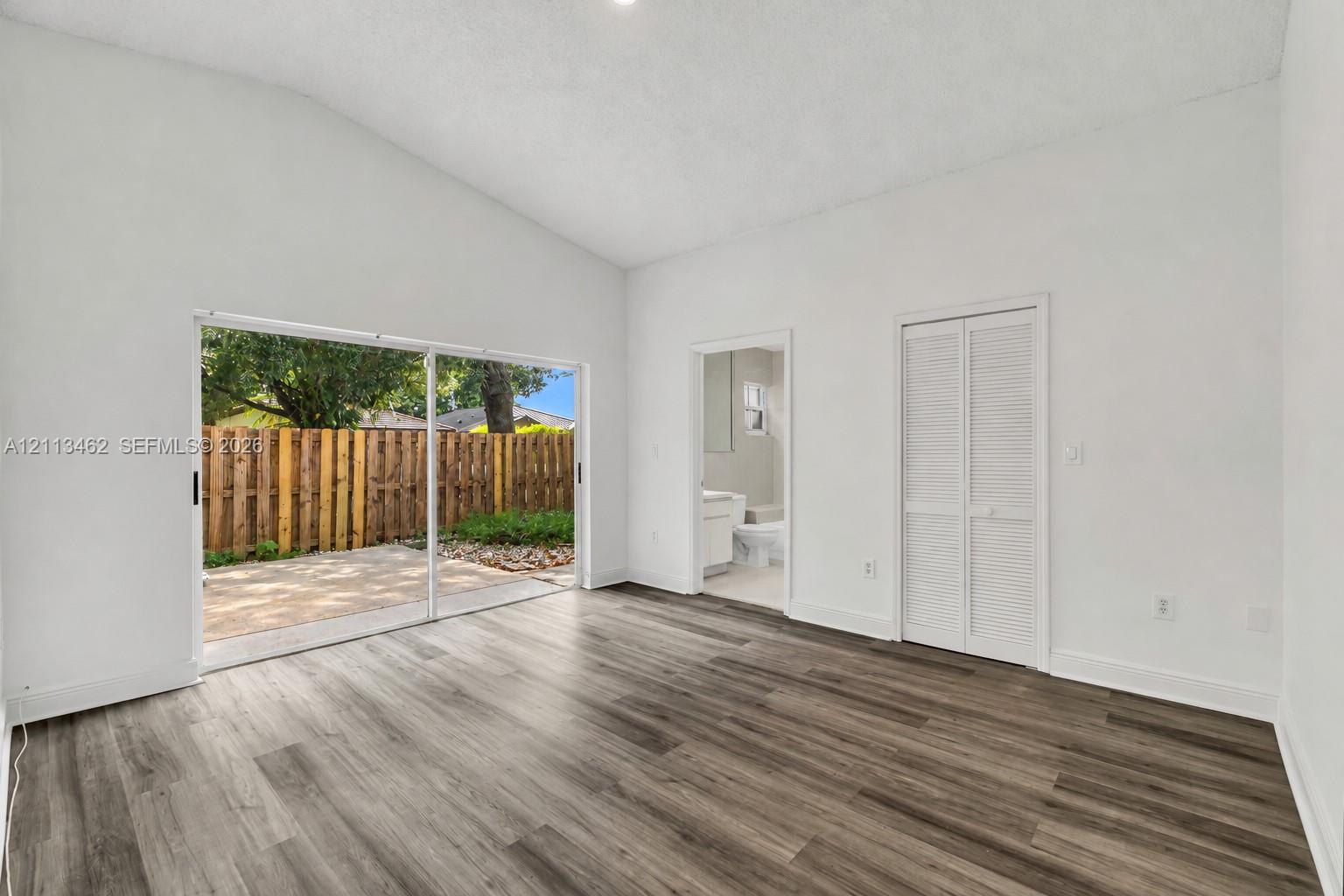 Vaulted ceiling, wood-finish flooring, sliding glass door, and louvered closet doors