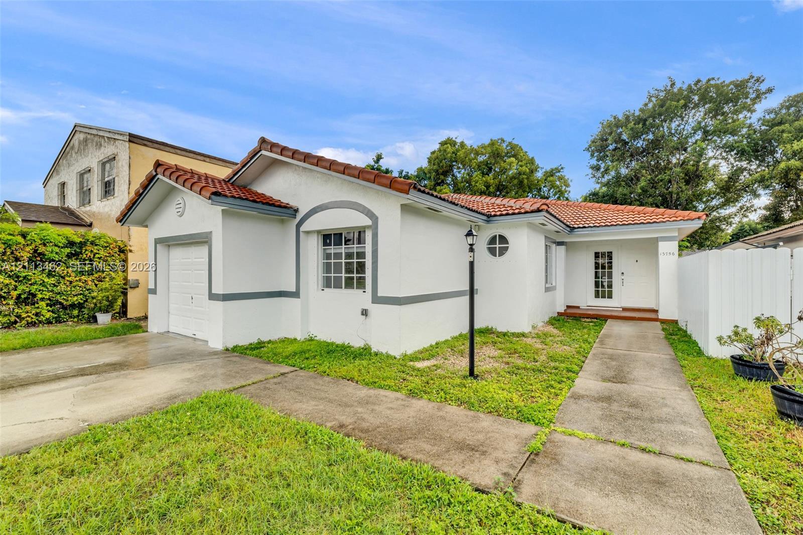 Single-story exterior featuring white stucco siding, a tiled roof, an integrated one-car garage, and a glass-panel front entry door
