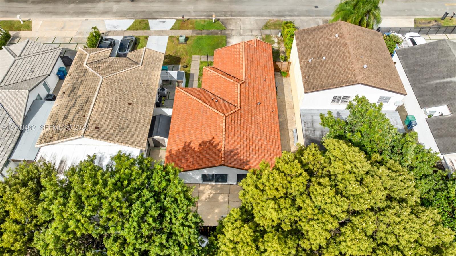 Aerial perspective of residence featuring a multi-gabled clay tile roof, concrete driveway, and established perimeter landscaping