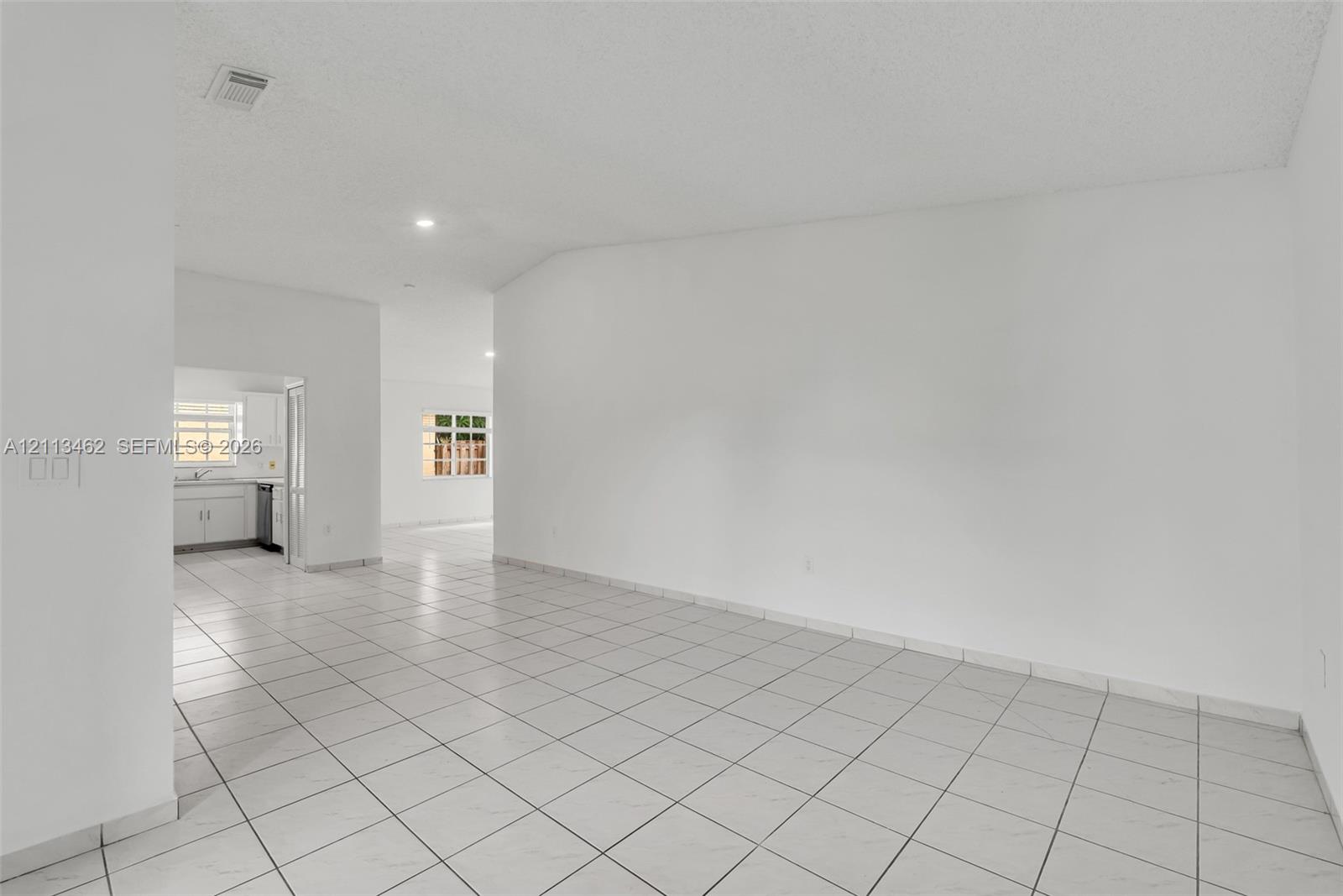 Open interior featuring neutral wall paint, white tile flooring, and vaulted ceilings
