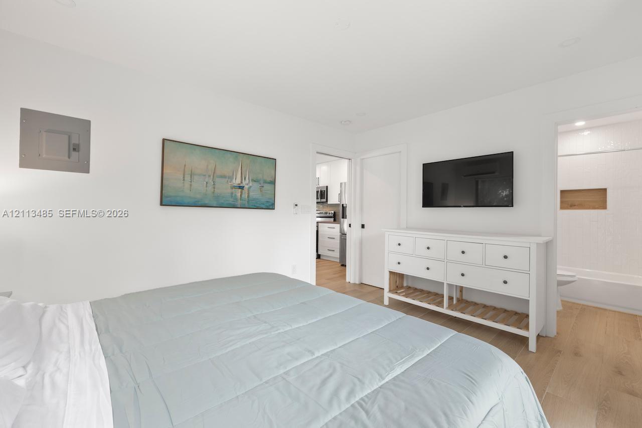 Interior space featuring wood-finish flooring, neutral walls, recessed lighting, and a doorway revealing a tiled shower area with a built-in recessed shelf