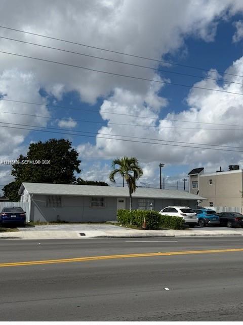 Single-story exterior featuring a concrete driveway, metal window security bars, and a mature palm tree