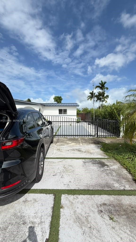 Concrete paver driveway with integrated turf, metal perimeter fencing, and exterior house facade