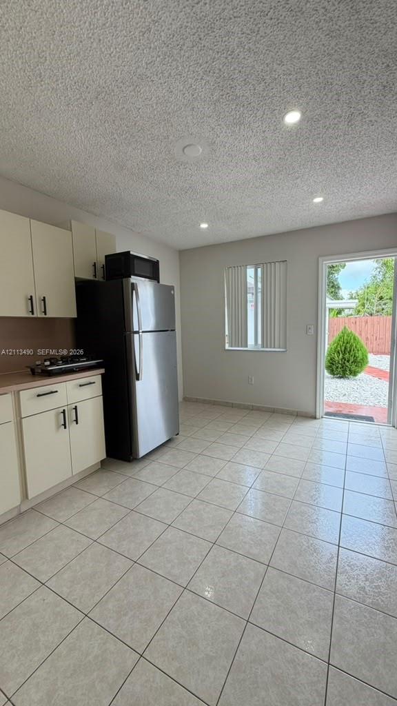 Kitchen featuring light-toned cabinetry, stainless steel refrigerator, tile flooring, and recessed lighting Kitchen featuring light-toned cabinetry, stainless steel refrigerator, tile flooring, and recessed lighting