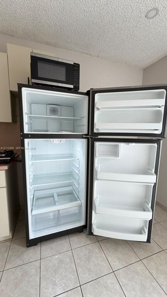 Top-mount stainless steel refrigerator with adjustable interior shelving, clear storage drawers, and door bins, featuring an integrated microwave above Top-mount stainless steel refrigerator with adjustable interior shelving, clear storage drawers, and door bins, featuring an integrated microwave above