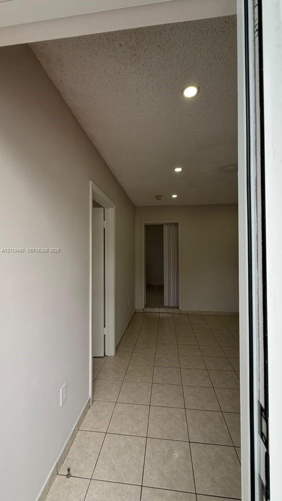 Interior hallway featuring neutral wall finishes, tile flooring, recessed ceiling lighting, and a bi-fold door Interior hallway featuring neutral wall finishes, tile flooring, recessed ceiling lighting, and a bi-fold door