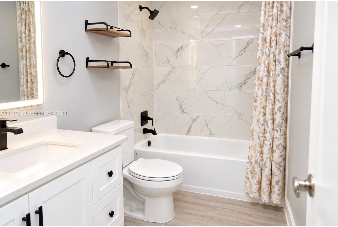 White vanity with stone-composite countertop, matte black fixtures, built-in floating wall shelves, and floor-to-ceiling tile shower surround White vanity with stone-composite countertop, matte black fixtures, built-in floating wall shelves, and floor-to-ceiling tile shower surround