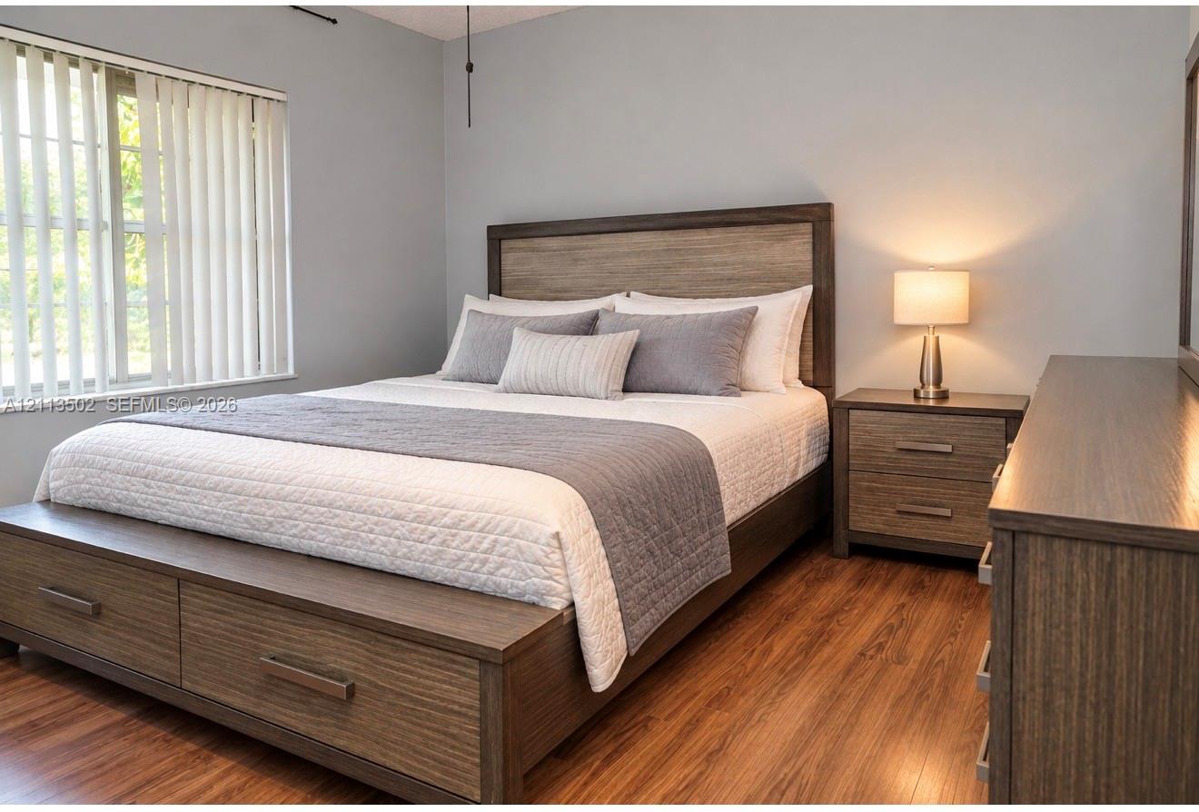 Bedroom featuring wood-finish flooring and vertical window blinds Bedroom featuring wood-finish flooring and vertical window blinds