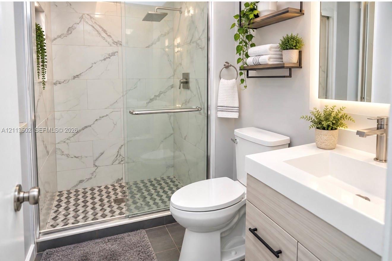 Walk-in shower with stone-finish tile surround and rain-style showerhead, glass enclosure, vanity with integrated basin and matte black hardware, and wall-mounted shelving Walk-in shower with stone-finish tile surround and rain-style showerhead, glass enclosure, vanity with integrated basin and matte black hardware, and wall-mounted shelving