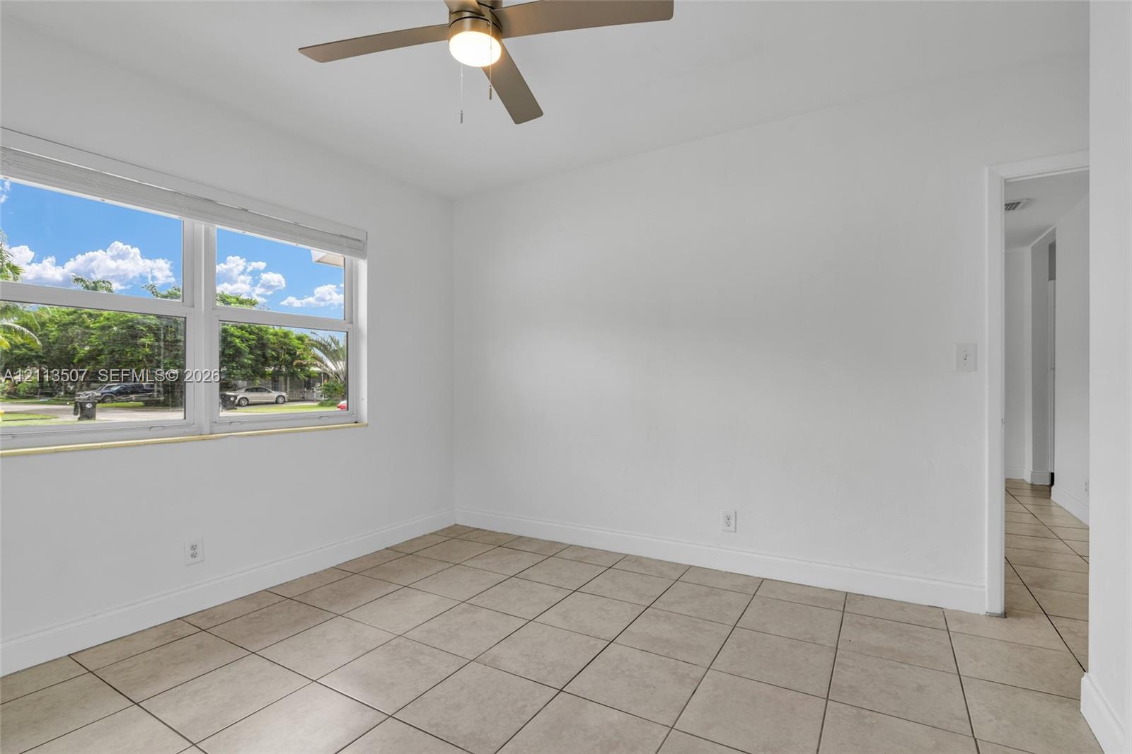 Neutral-toned tile flooring, large multi-pane window, and ceiling fan with integrated lighting
