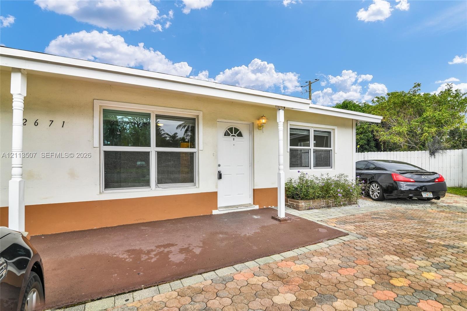 Exterior facade featuring stucco siding, a covered front porch, multi-pane windows, and a paved brick driveway Exterior facade featuring stucco siding, a covered front porch, multi-pane windows, and a paved brick driveway