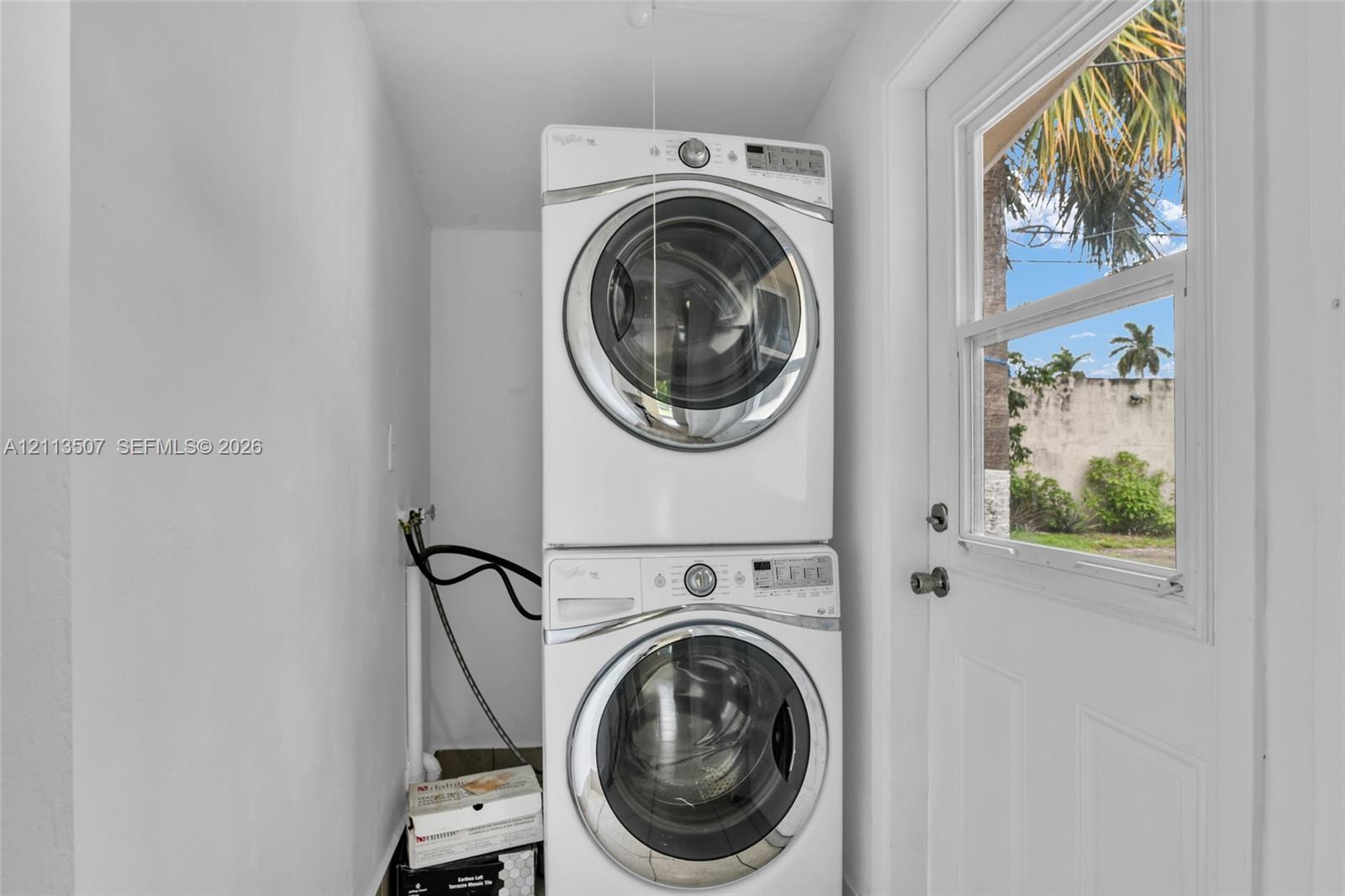 Laundry area featuring a white stackable washer and dryer unit and a glass-paneled exterior door