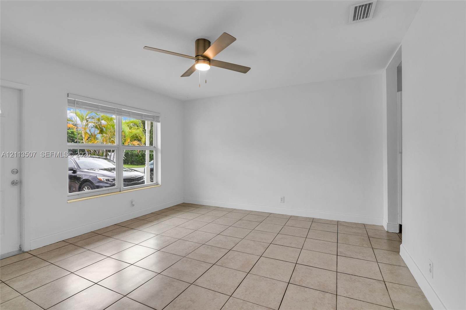 Neutral interior space featuring tile flooring, a metallic ceiling fan with integrated lighting, and large windows Neutral interior space featuring tile flooring, a metallic ceiling fan with integrated lighting, and large windows