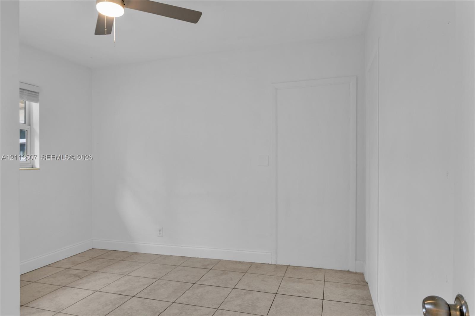 Neutral-toned interior featuring ceramic tile flooring, a window with horizontal blinds, and a ceiling fan with integrated lighting Neutral-toned interior featuring ceramic tile flooring, a window with horizontal blinds, and a ceiling fan with integrated lighting