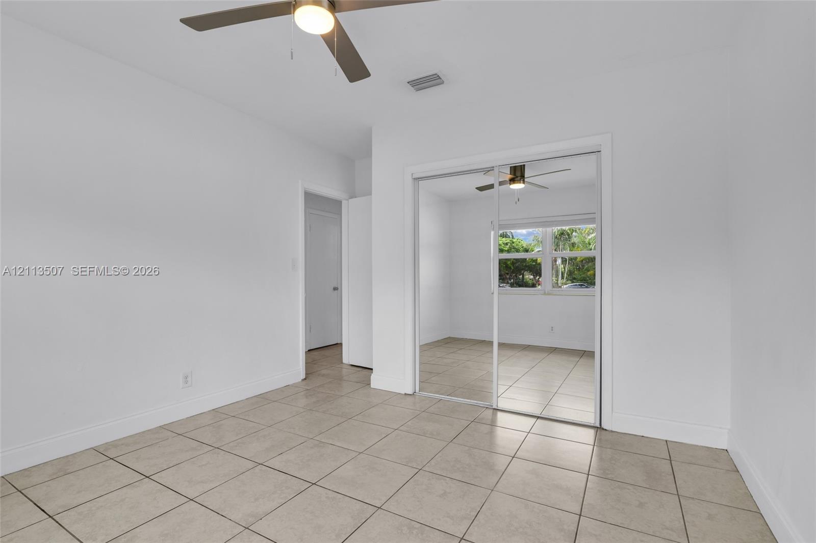 Tile flooring, ceiling fan with integrated lighting, and sliding mirrored closet doors