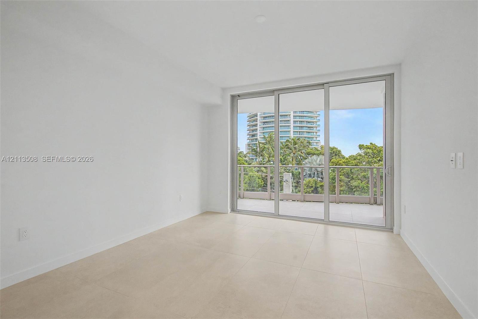 Neutral-toned tile flooring, floor-to-ceiling glass sliding doors, and a private balcony with metal railing