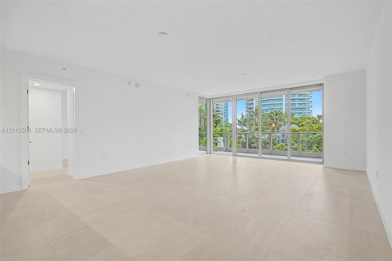 Open-concept interior featuring large-format tile flooring, floor-to-ceiling glass sliding doors, and neutral wall finishes
