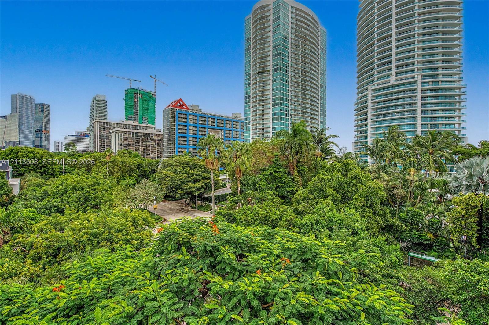 Urban landscape featuring high-rise buildings, mature tropical trees, and manicured greenery Urban landscape featuring high-rise buildings, mature tropical trees, and manicured greenery
