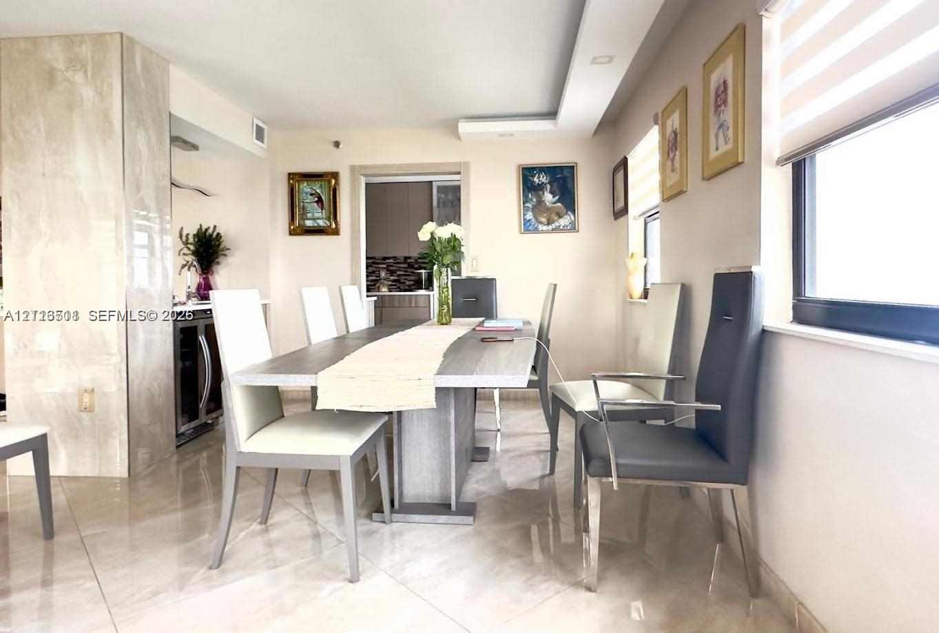 Dining area featuring polished stone-finish flooring, a full-height stone-clad column, recessed ceiling lighting, and built-in under-counter beverage refrigeration