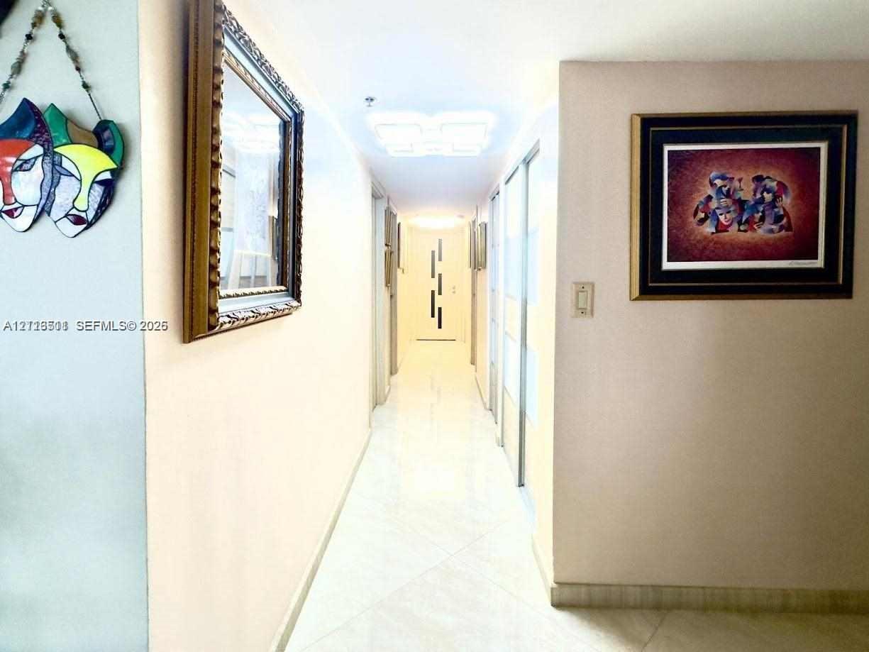 Hallway featuring tile flooring, ceiling-mounted light fixtures, and floor-to-ceiling mirrored closet doors