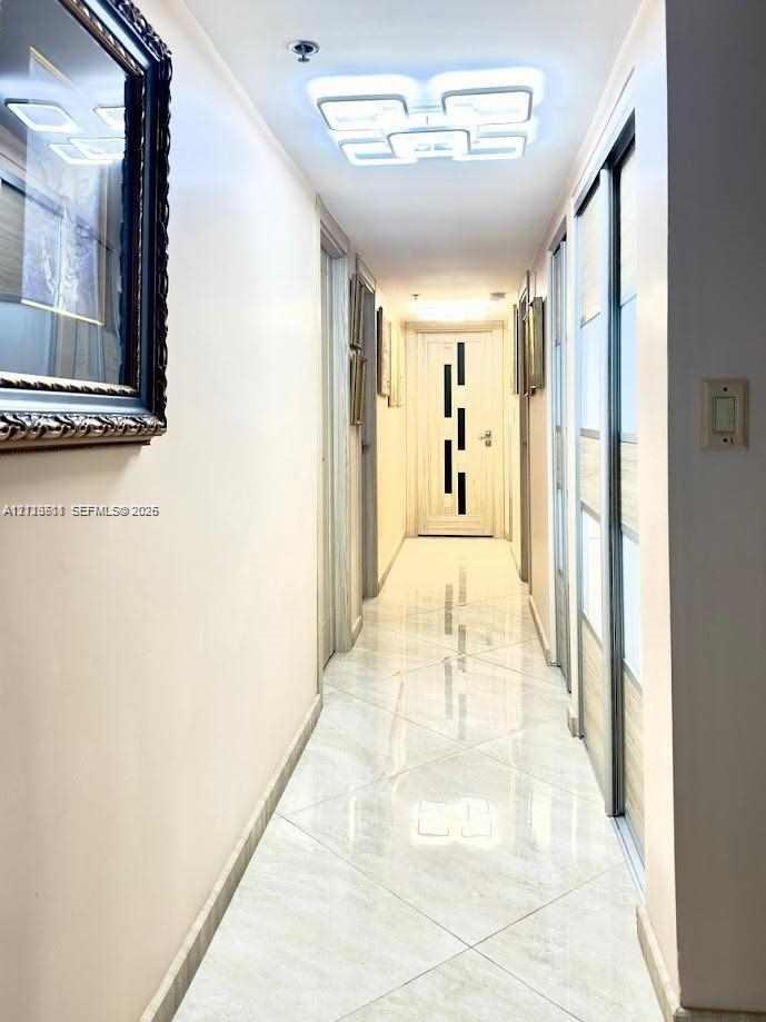 Hallway featuring high-gloss tile flooring, geometric LED ceiling light fixture, and sliding door closet with wood-finish paneling
