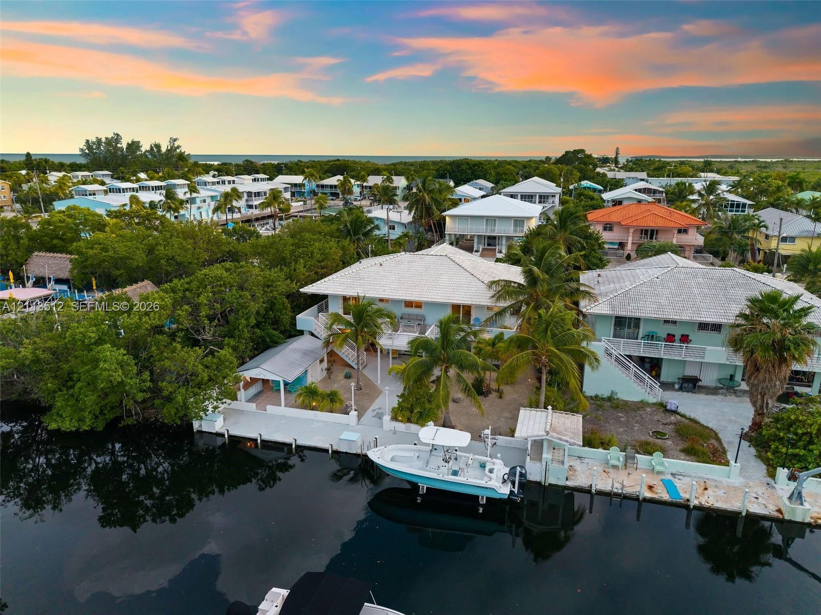 Waterfront residence featuring a private boat dock, concrete seawall, and elevated exterior staircase, situated on a canal with direct water access