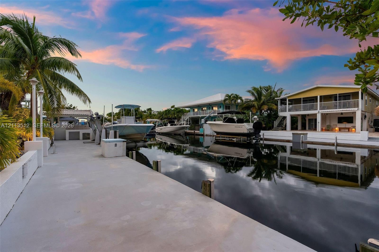 Concrete deep-water dock featuring multiple boat slips, integrated utility pilings, and direct canal access
