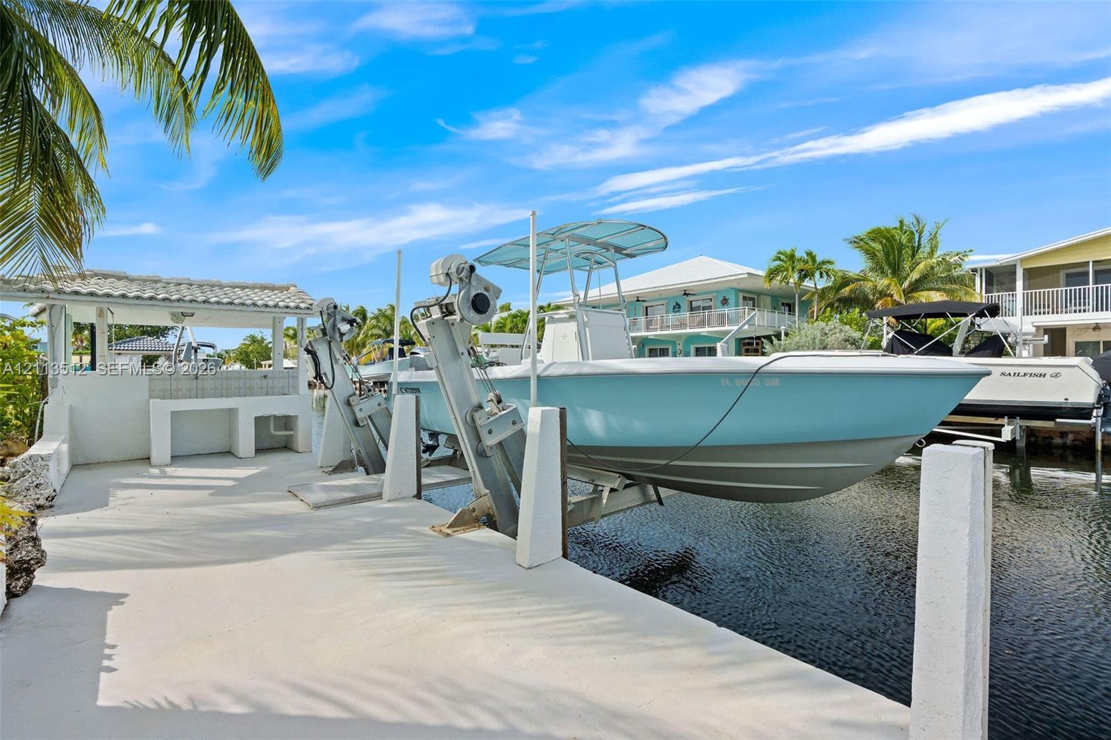 Private dock featuring a boat lift, concrete slip, and a covered cleaning station