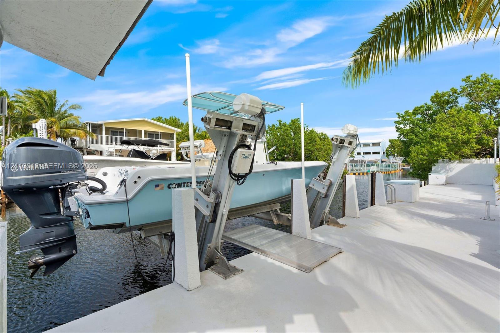 Private boat dock featuring an integrated mechanical boat lift and a paved walkway