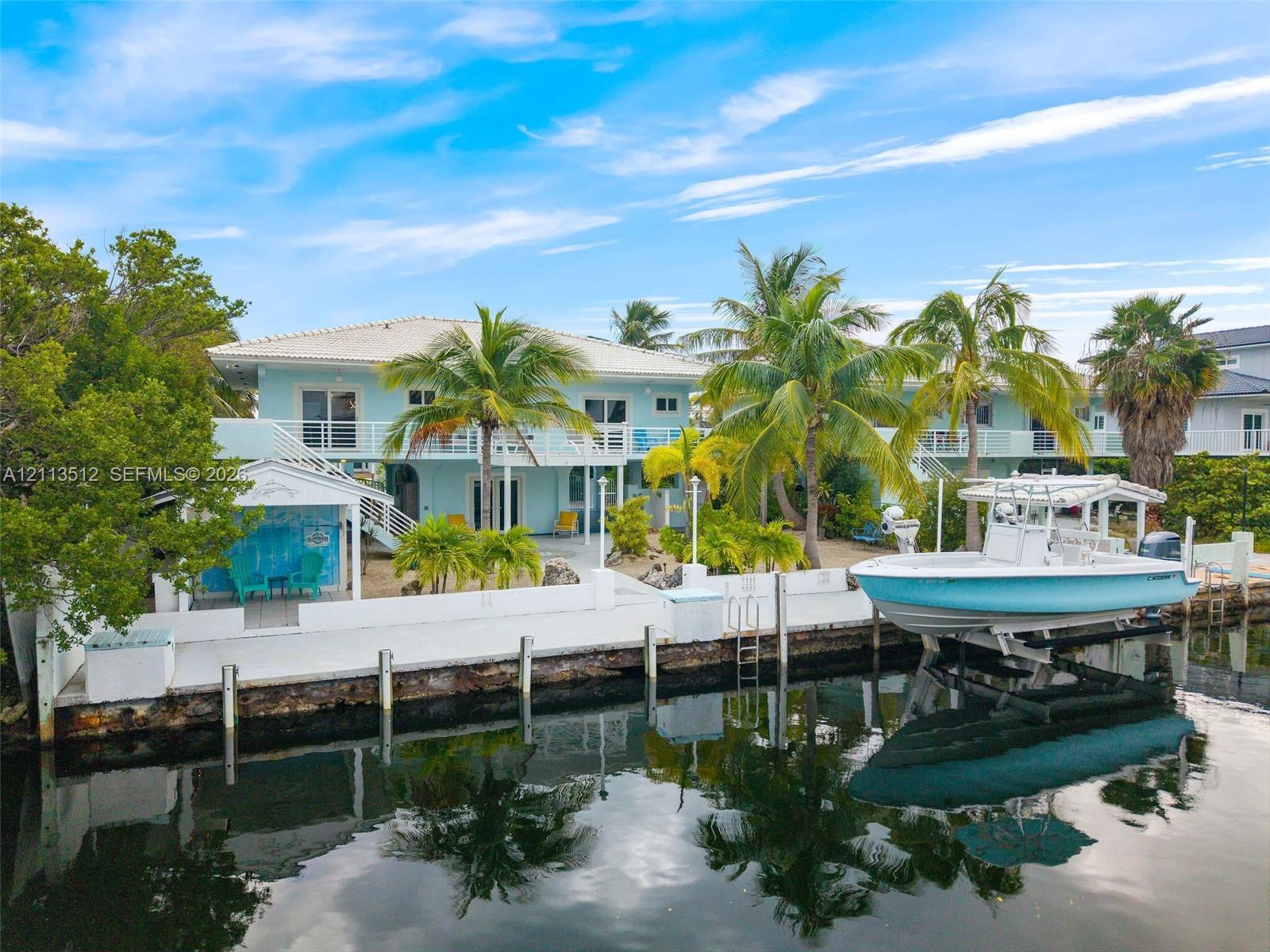 Waterfront property featuring a private boat lift, a concrete bulkhead, paved hardscaping, and an elevated terrace