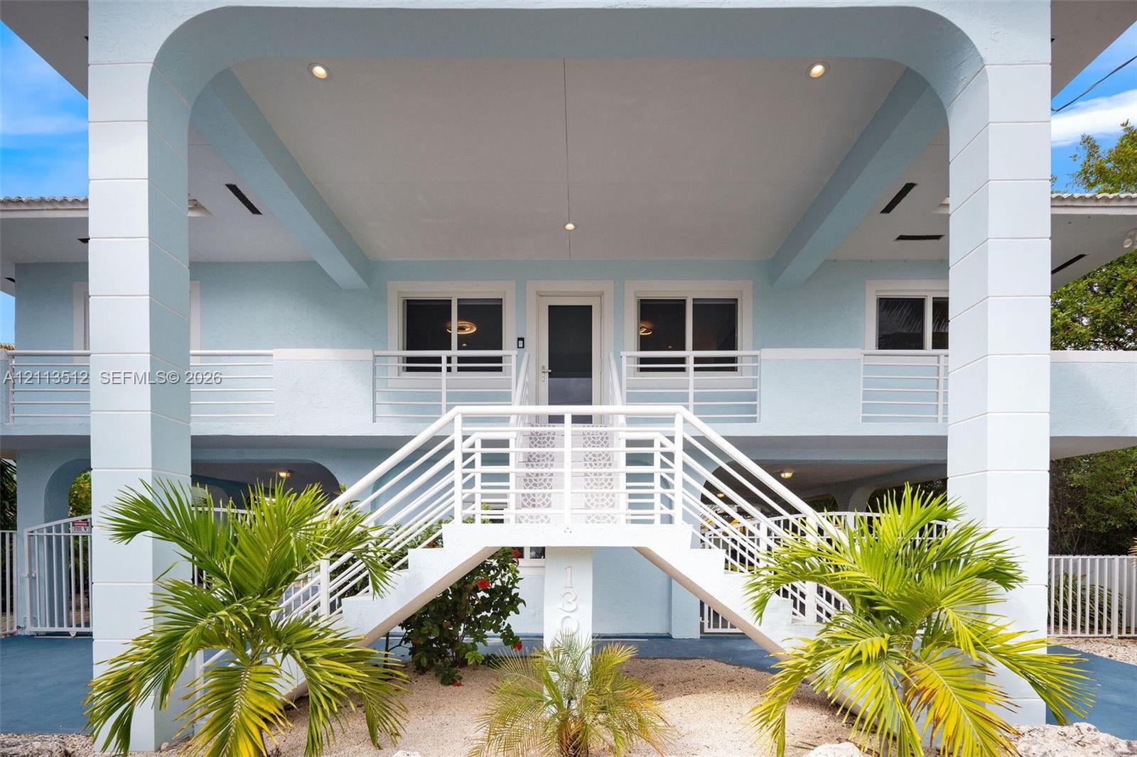 Stilted exterior structure featuring a symmetrical staircase, arched support columns, recessed ceiling lighting, and horizontal metal railing