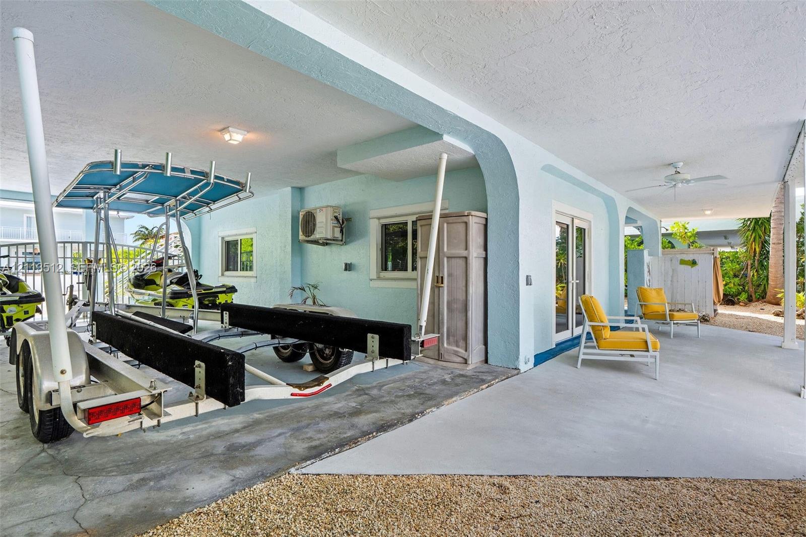 Covered patio featuring concrete flooring, structural arched supports, recessed ceiling lighting, and a built-in exterior storage cabinet