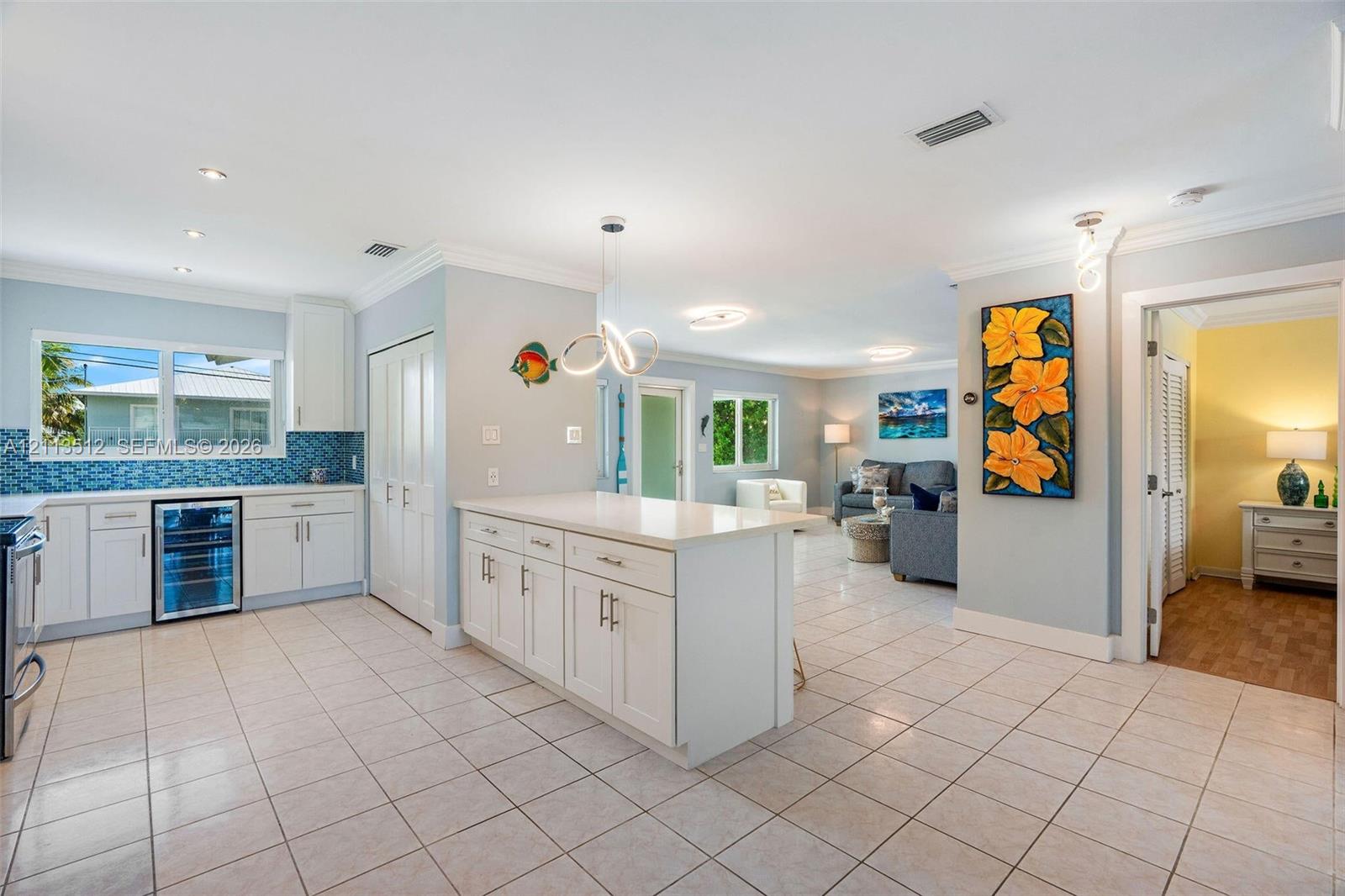 Kitchen featuring white cabinetry, center island with stone countertop, tile backsplash, built-in beverage refrigerator, and tile flooring