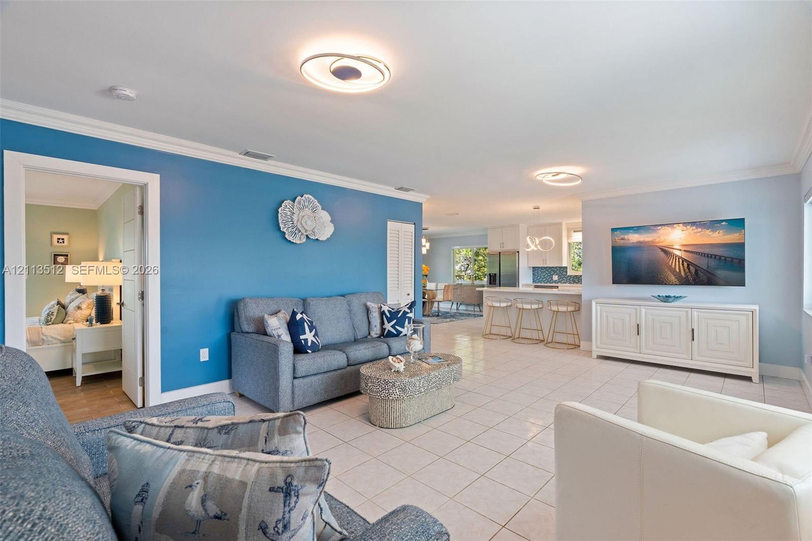 Open-concept interior featuring neutral tile flooring, recessed circular lighting fixtures, and crown molding