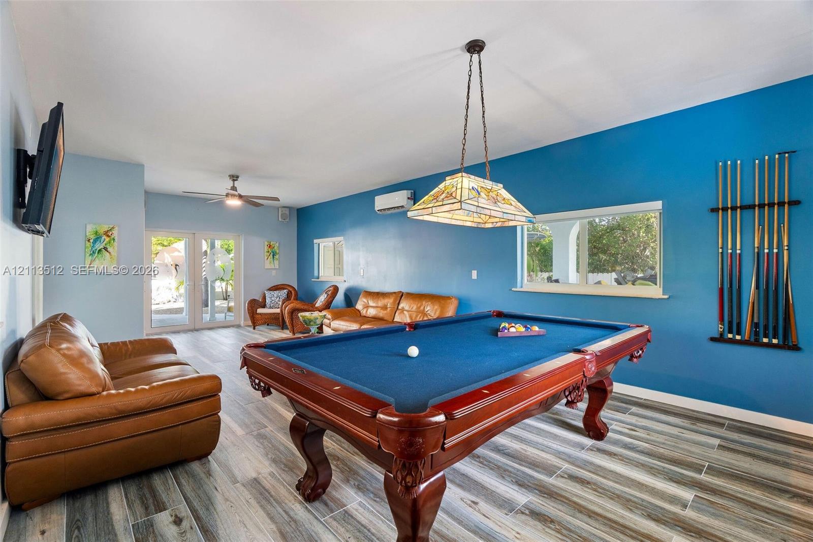 Wood-finish flooring, stained-glass pendant lighting, wall-mounted ductless air conditioning unit, and glass-paneled exterior door