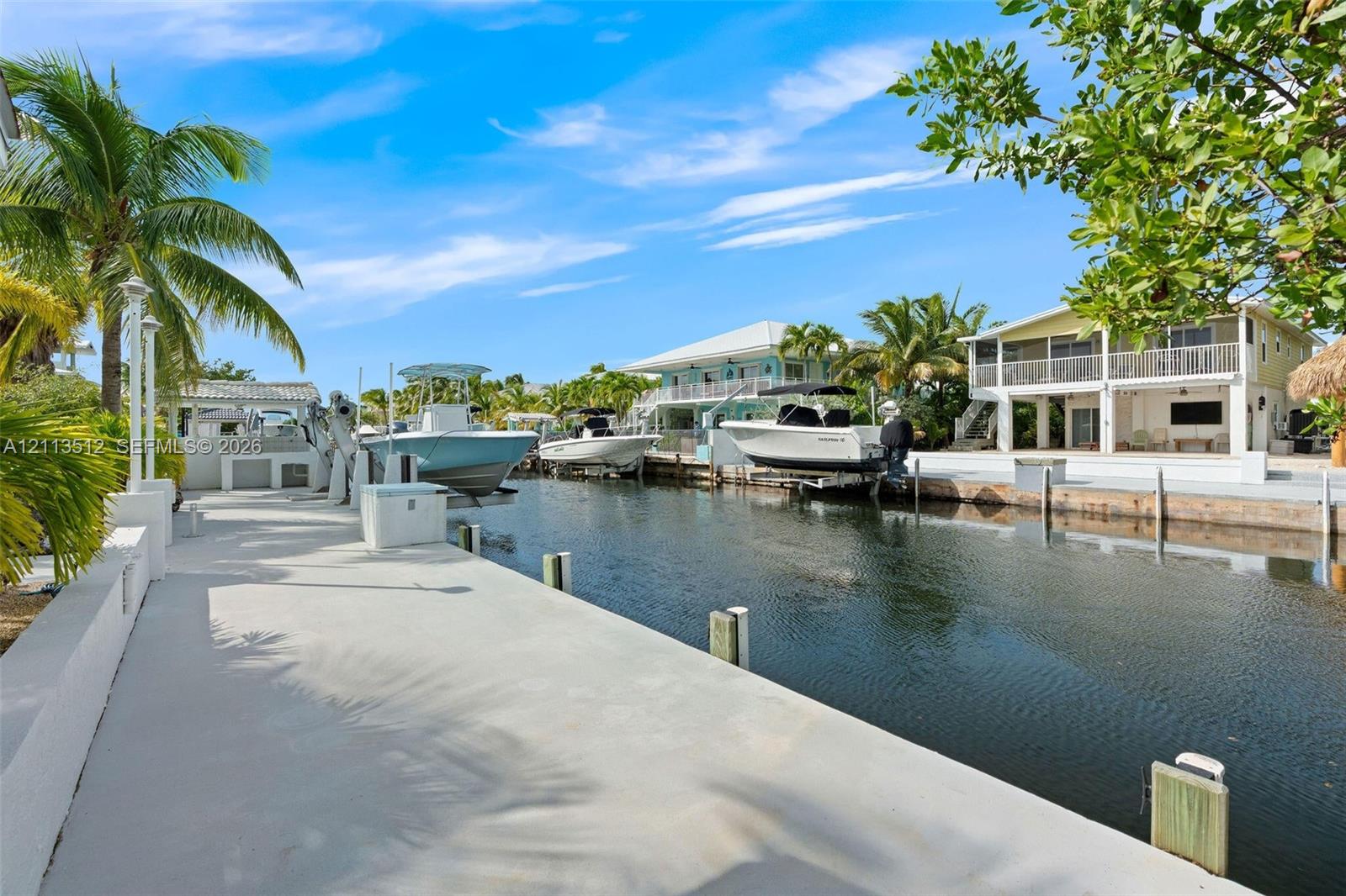 Concrete waterfront dock featuring boat lifts, utility pedestals, and access to a canal