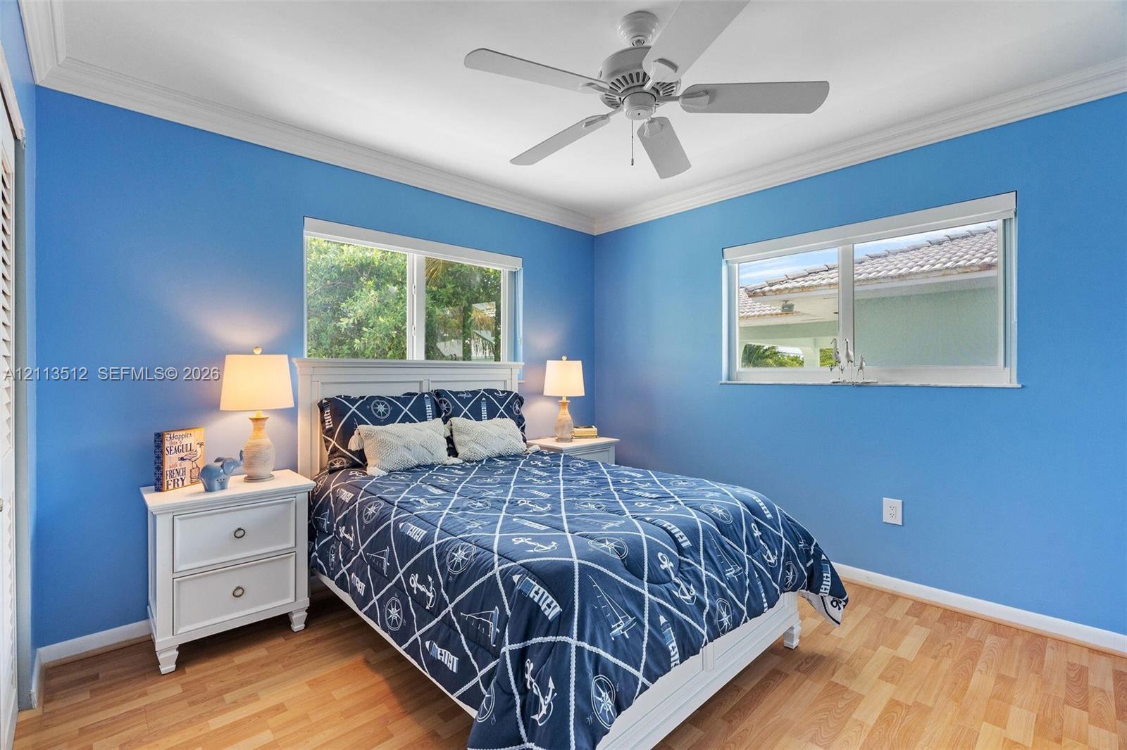 Wood-finish flooring, white ceiling fan, and crown molding