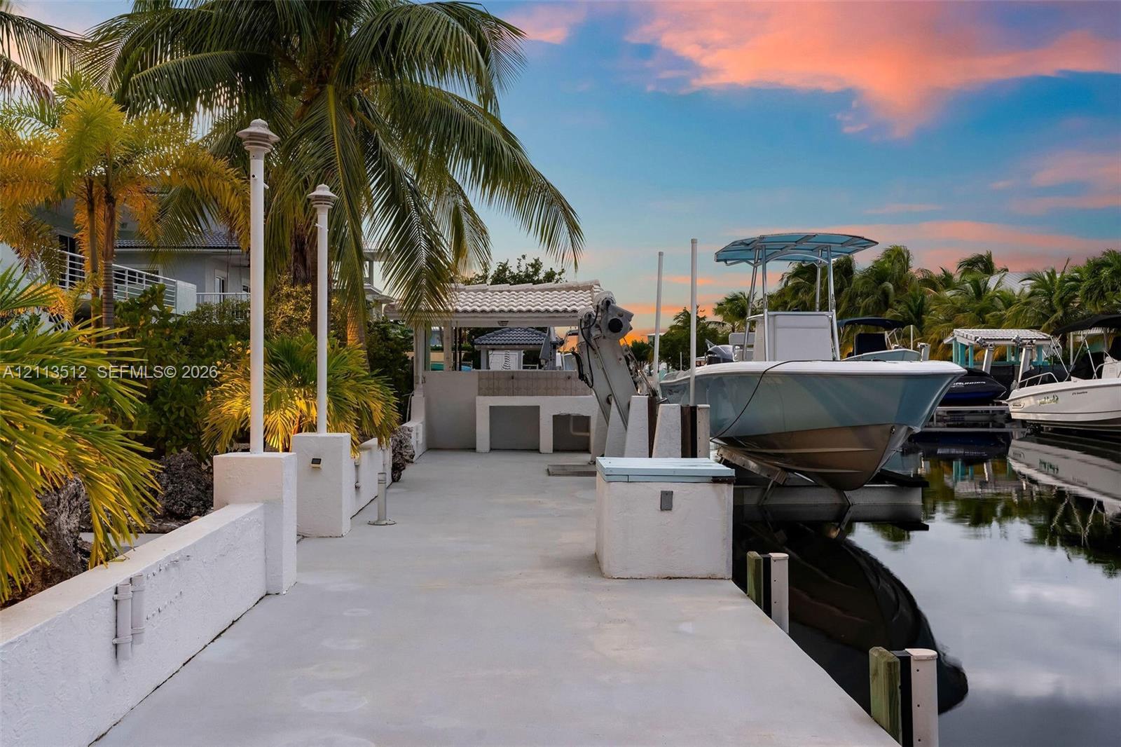 Concrete dock featuring a boat lift, built-in storage unit, and pedestal lighting