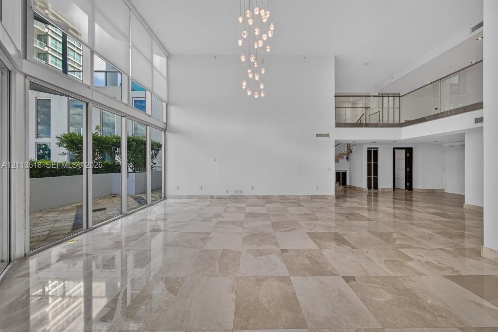 Double-height ceilings, floor-to-ceiling glass wall, polished stone flooring, multi-tiered pendant light fixture, and second-level mezzanine with glass railing Double-height ceilings, floor-to-ceiling glass wall, polished stone flooring, multi-tiered pendant light fixture, and second-level mezzanine with glass railing