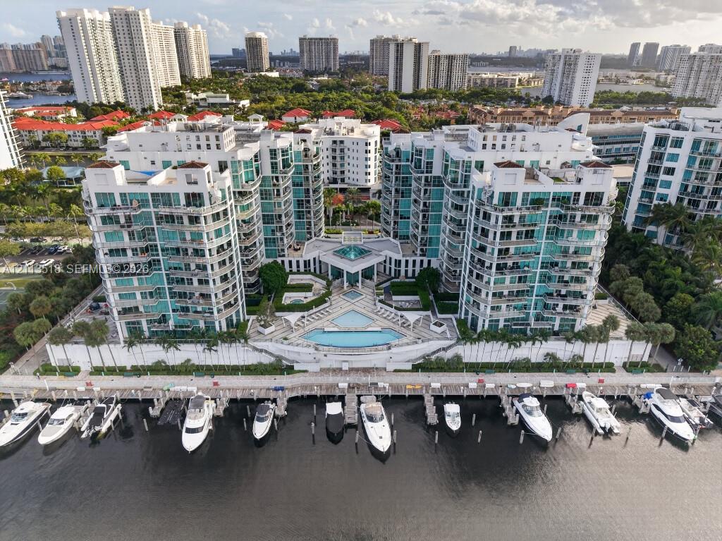 Multi-story residential complex featuring private deep-water boat slips, expansive waterfront sun deck, tiered swimming pool, and glass-railed balconies