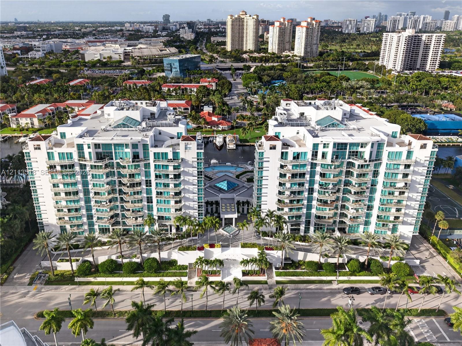 High-rise waterfront residential complex featuring private balconies, an on-site swimming pool, deep-water boat slips, and extensive perimeter landscaping