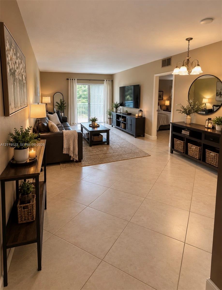 Open-concept room featuring large-format neutral tile flooring, sliding glass doors, and a multi-arm overhead light fixture Open-concept room featuring large-format neutral tile flooring, sliding glass doors, and a multi-arm overhead light fixture