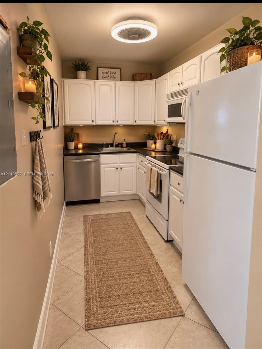 Kitchen featuring white cabinetry, dark countertops, tile flooring, stainless steel dishwasher, and a flush-mount overhead light fixture Kitchen featuring white cabinetry, dark countertops, tile flooring, stainless steel dishwasher, and a flush-mount overhead light fixture